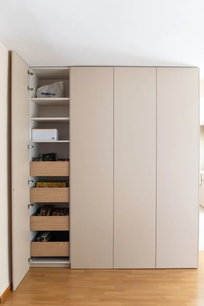Mueble de almacenaje a altura completa con una puerta abierta, baldas y cajones interiores.